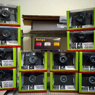 A stack of Holga cameras piled high on the shelf at Photolab of Berkeley. Come get yours!