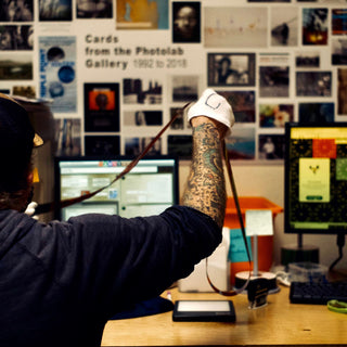 A technician wearing white gloves examines a strip of film negative at Photolab Berkeley before starting a project for a customer.