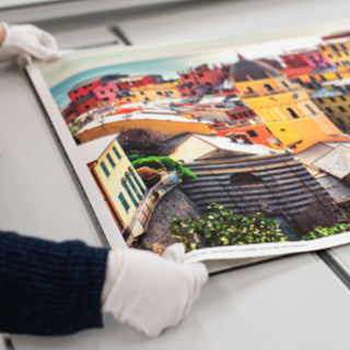 A technician handles a large fine art print of a European cityscape for a client at Photolab of Berkeley