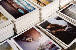 Many color and black & white photos arranged in stacks on a surface filling the frame.
