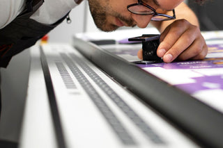 A technician examines a fine art print with an instrument for a client at Photolab of Berkeley