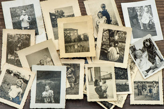 Vintage film prints in various states of children in black & white arranged on a table